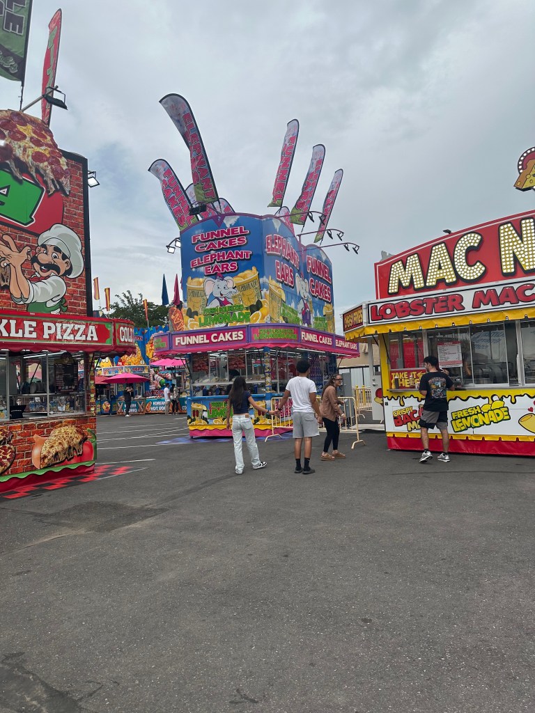 Colorful food booths lining a walkway at the New Mexico State Fair.