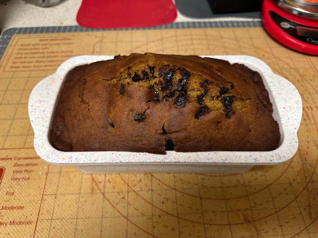 Homemade sugar-free pumpkin chocolate chip bread baked in a loaf pan with chocolate chips on top.